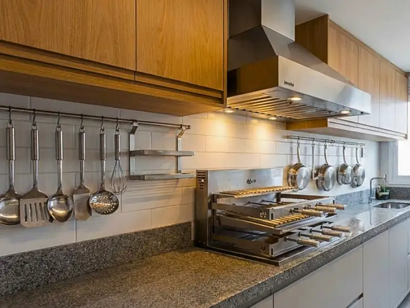Coifa de parede em inox instalada em cozinha planejada com armários amadeirados e utensílios.